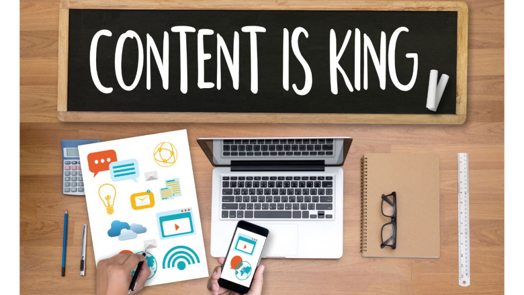 CONTENT IS KING（コンテンツが一番大事）と書かれた黒板とノートPC、コンテンツマーケティングにまつわるもののアイコンが書かれた紙、スマートフォンを操作している人の手元の画像